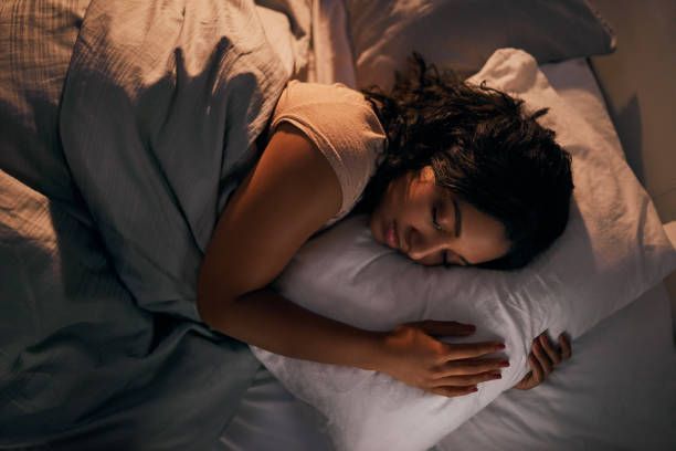 A woman is sleeping in a bed with a pillow and a blanket.