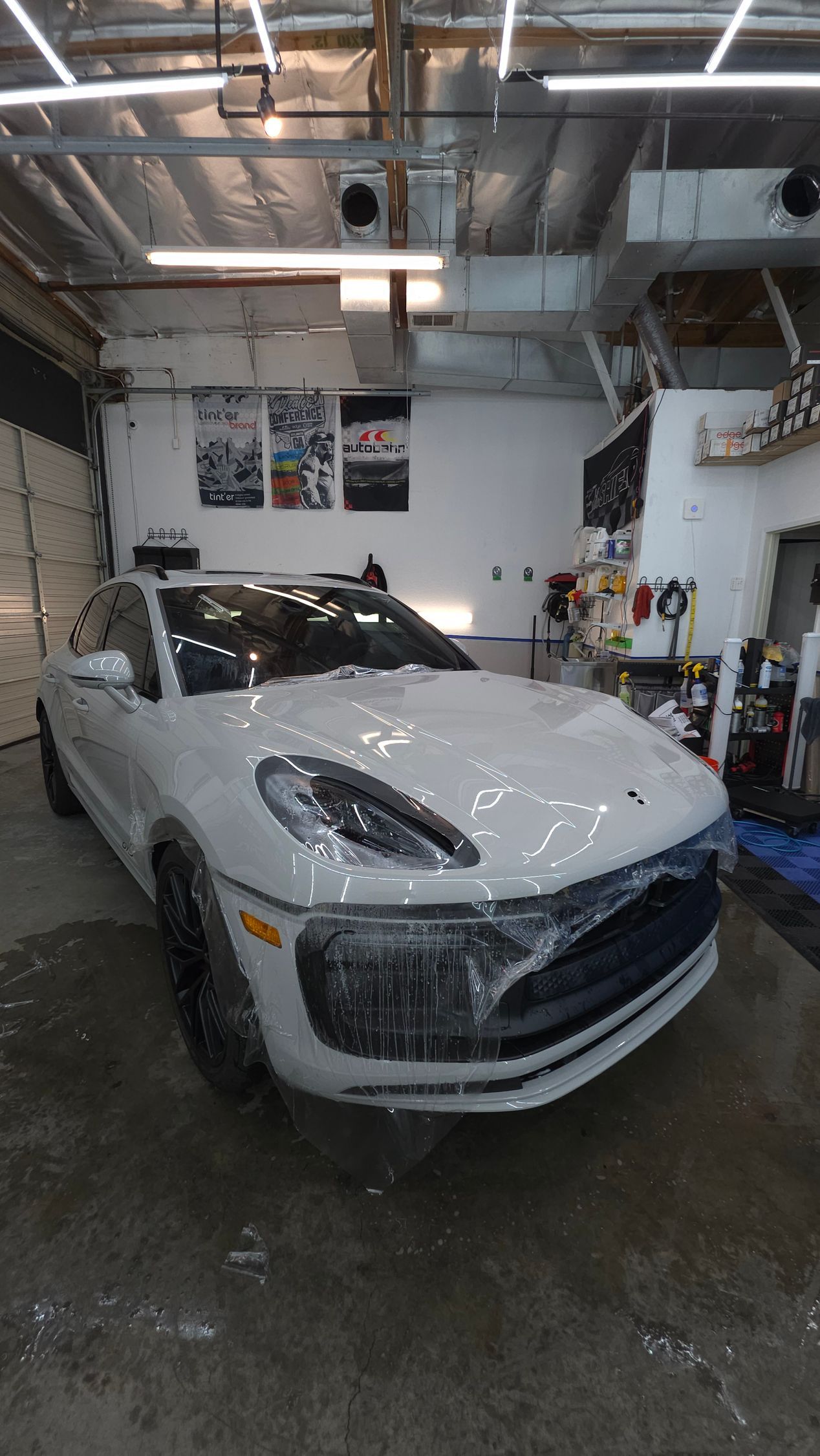 White Porsche Macan SUV in a garage, covered in protective film.