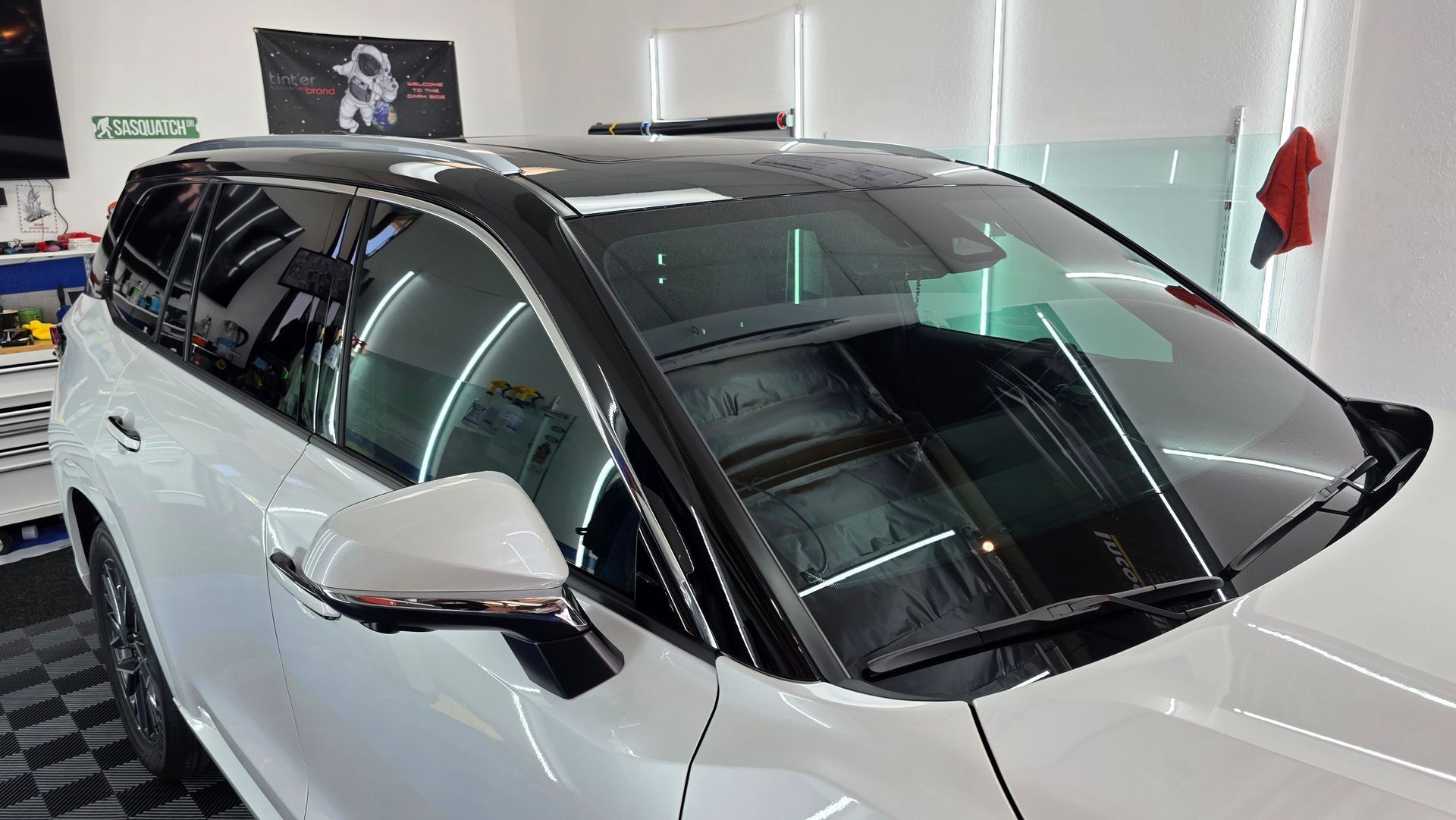 A white suv with a black roof is parked in a garage.