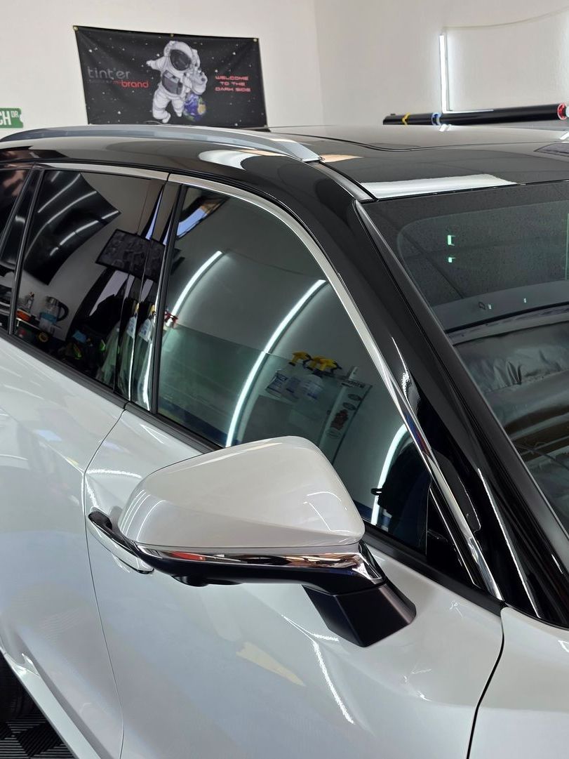 A white car with a black roof is parked in a garage.