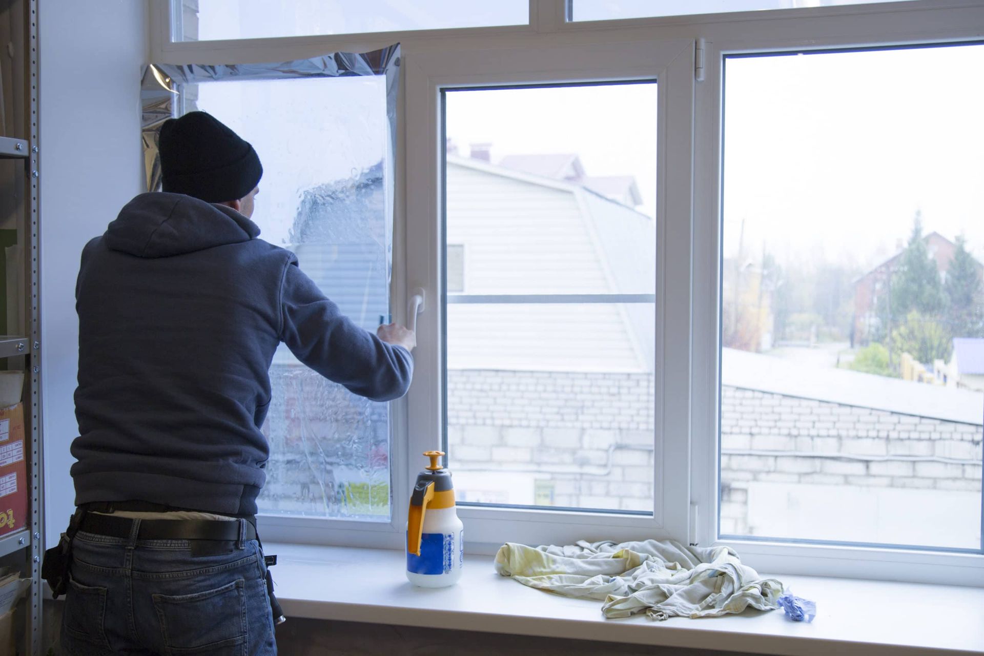 A man is cleaning a window with a spray bottle.