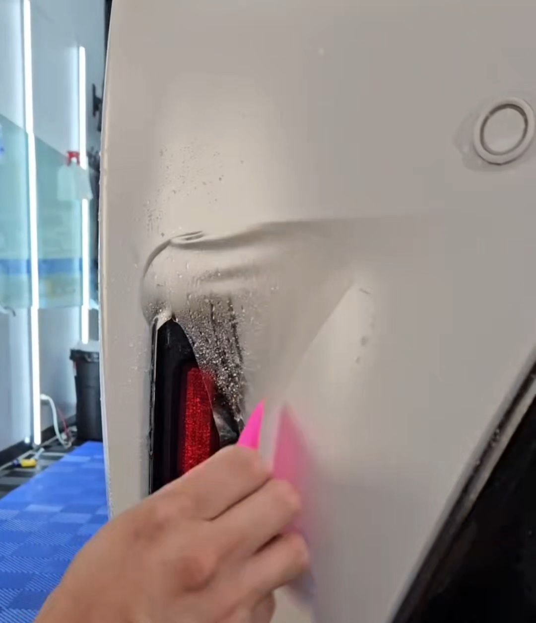 A person is wrapping a car with a pink sponge.