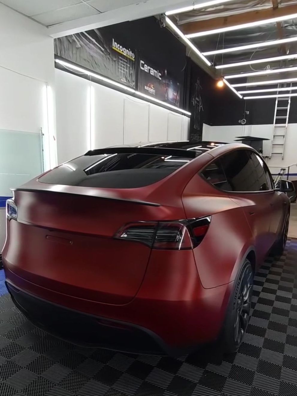 A red tesla model y is parked in a garage.