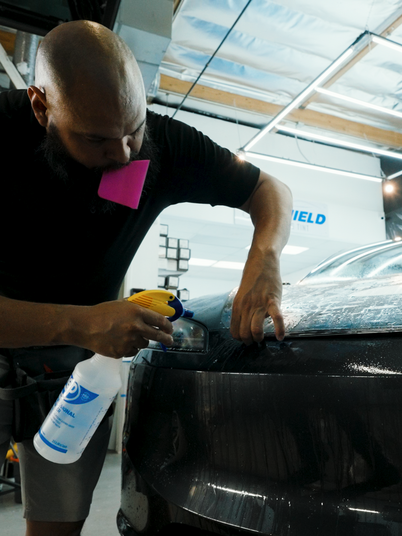 A man is spraying a car with a spray bottle.