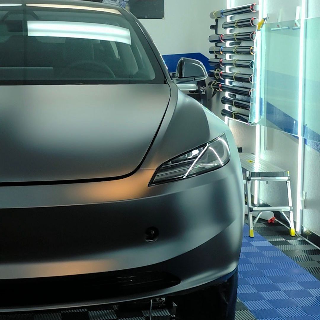A gray tesla model 3 is parked in a garage