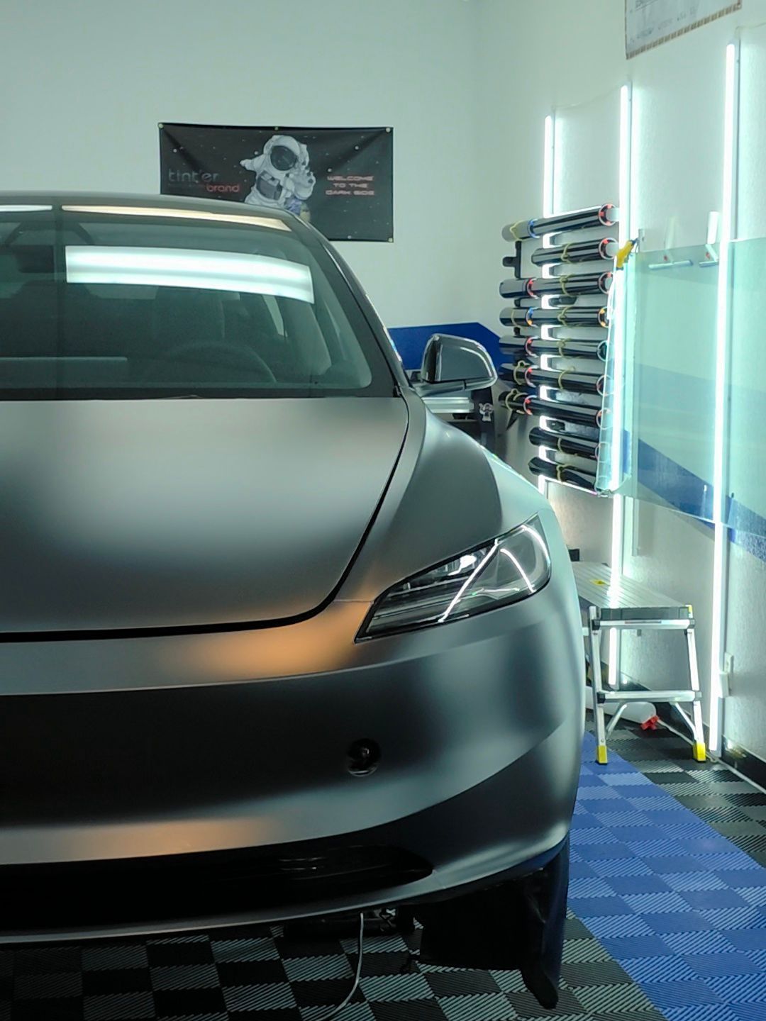 A gray tesla model 3 is parked in a garage