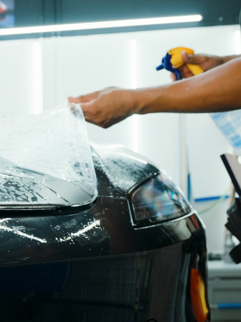 A person is spraying a car with a spray bottle.