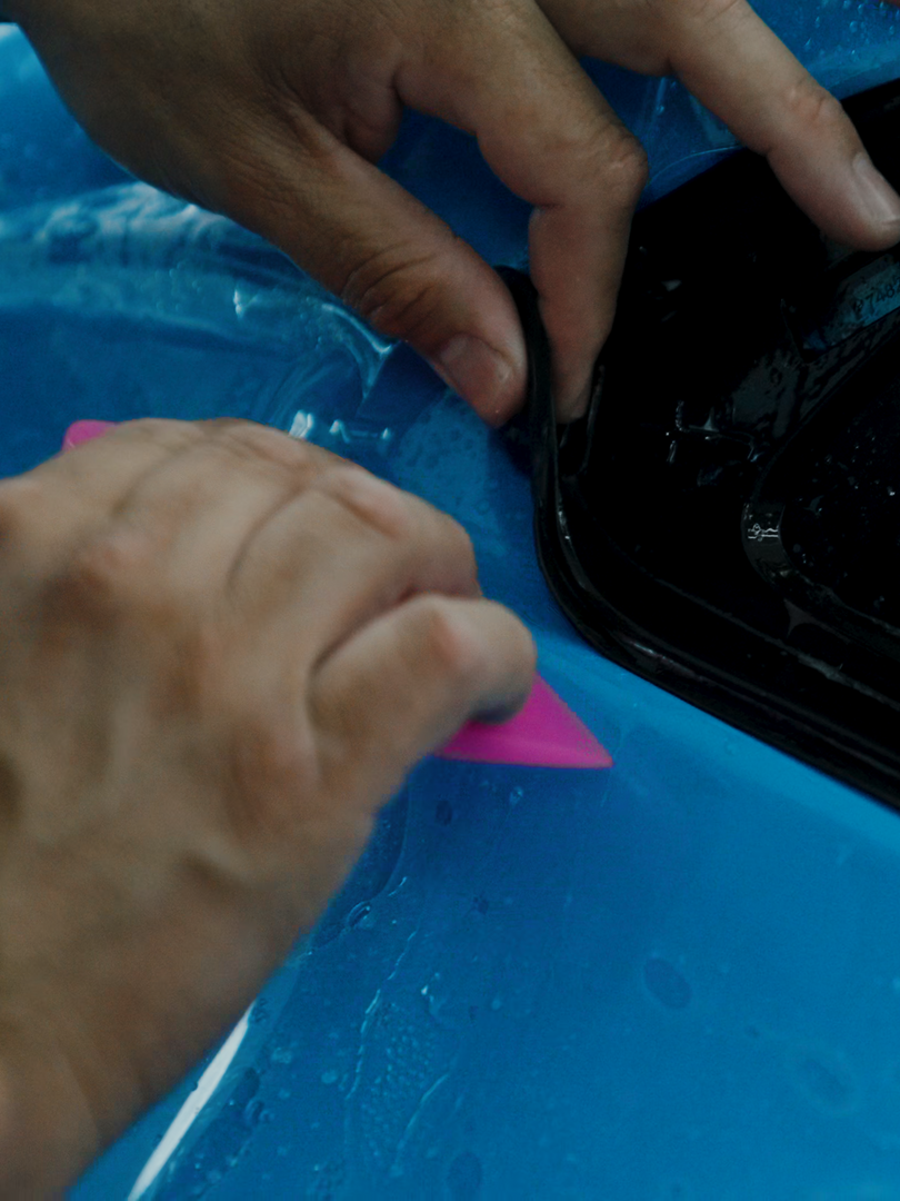 A person is holding a pink triangle on a blue surface