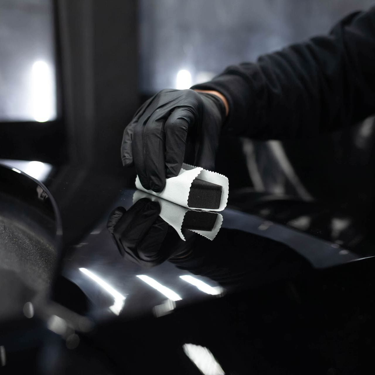 A person wearing black gloves is holding a white object
