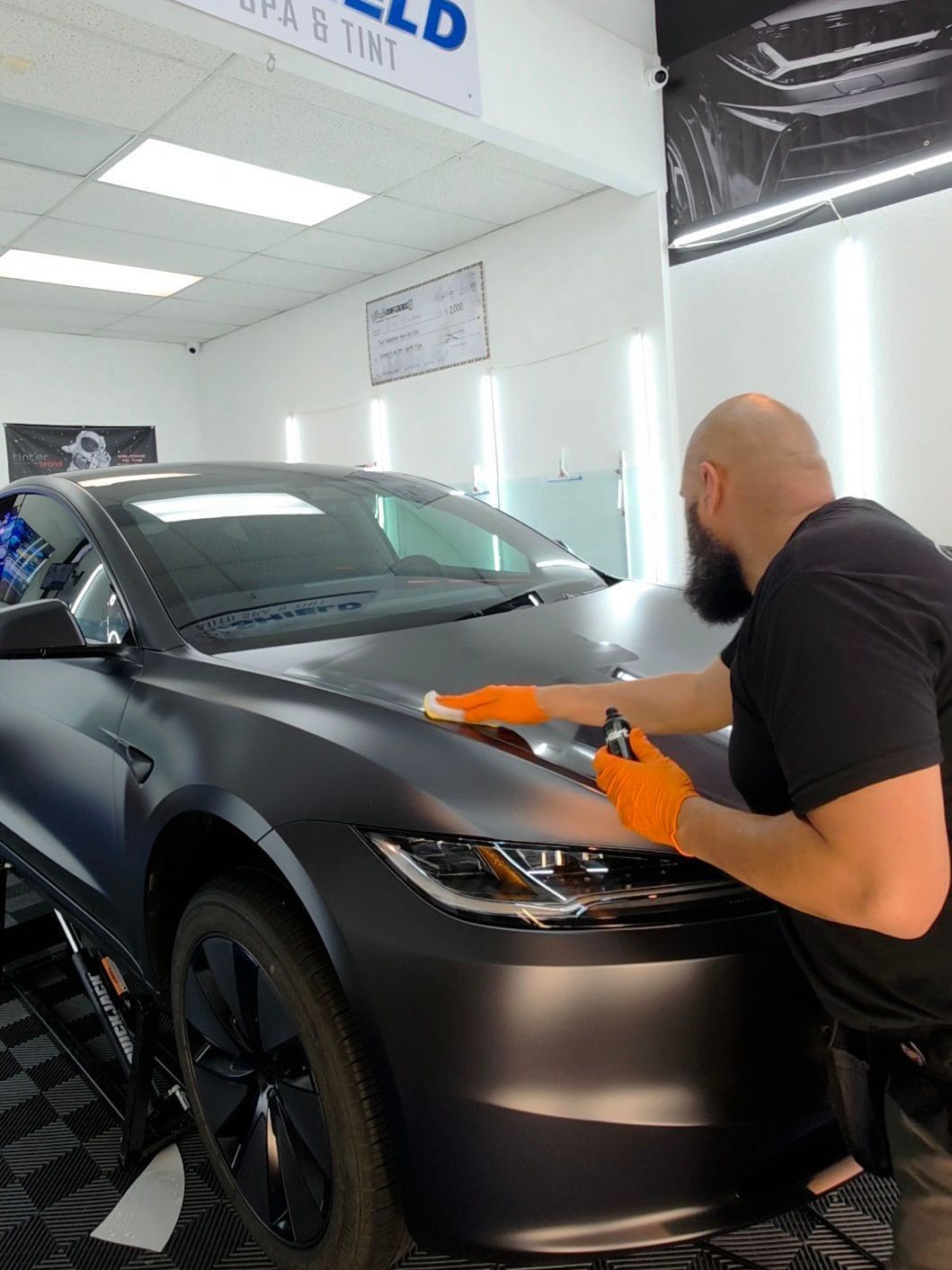 A man is cleaning the hood of a car in a garage.