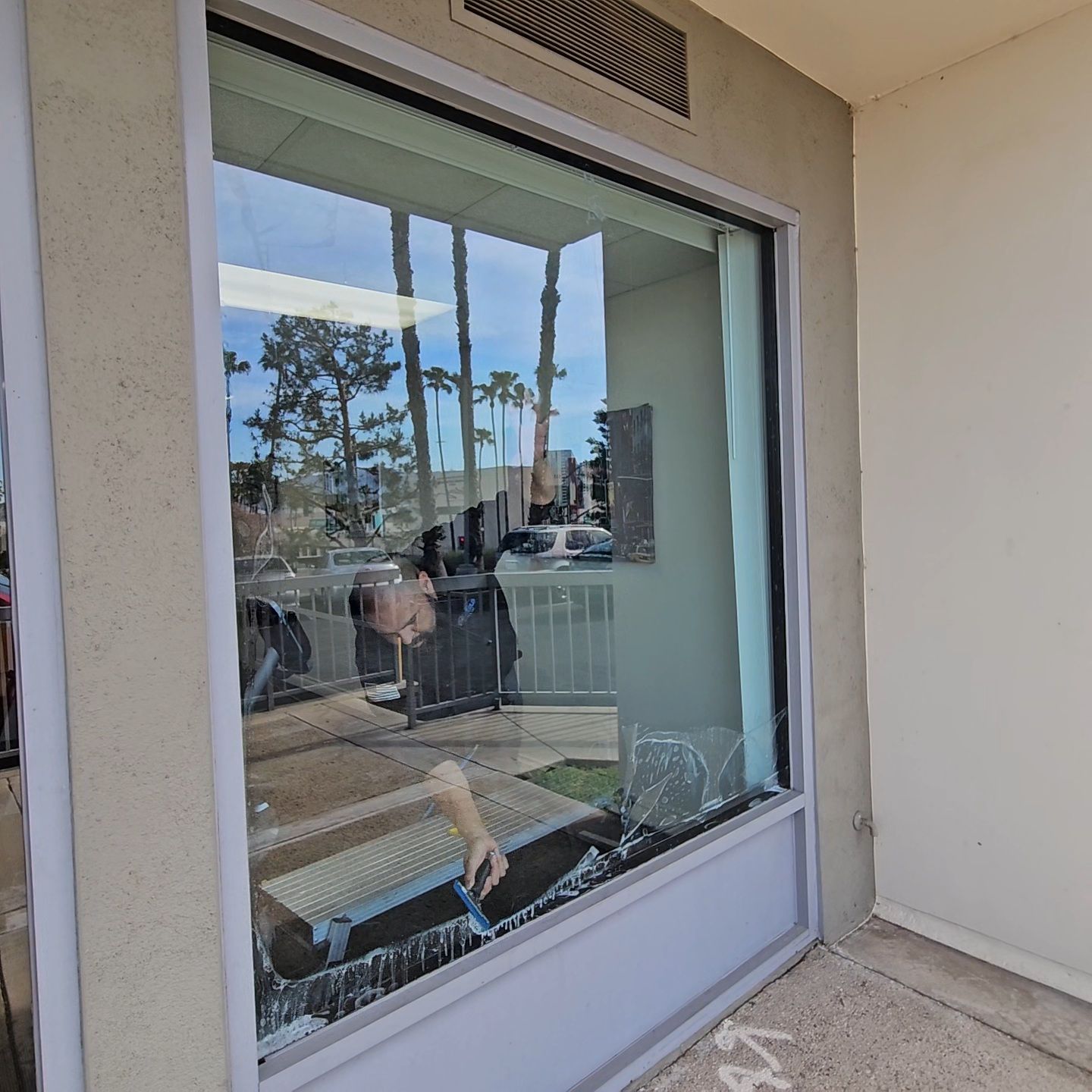 A person is cleaning a window outside of a building