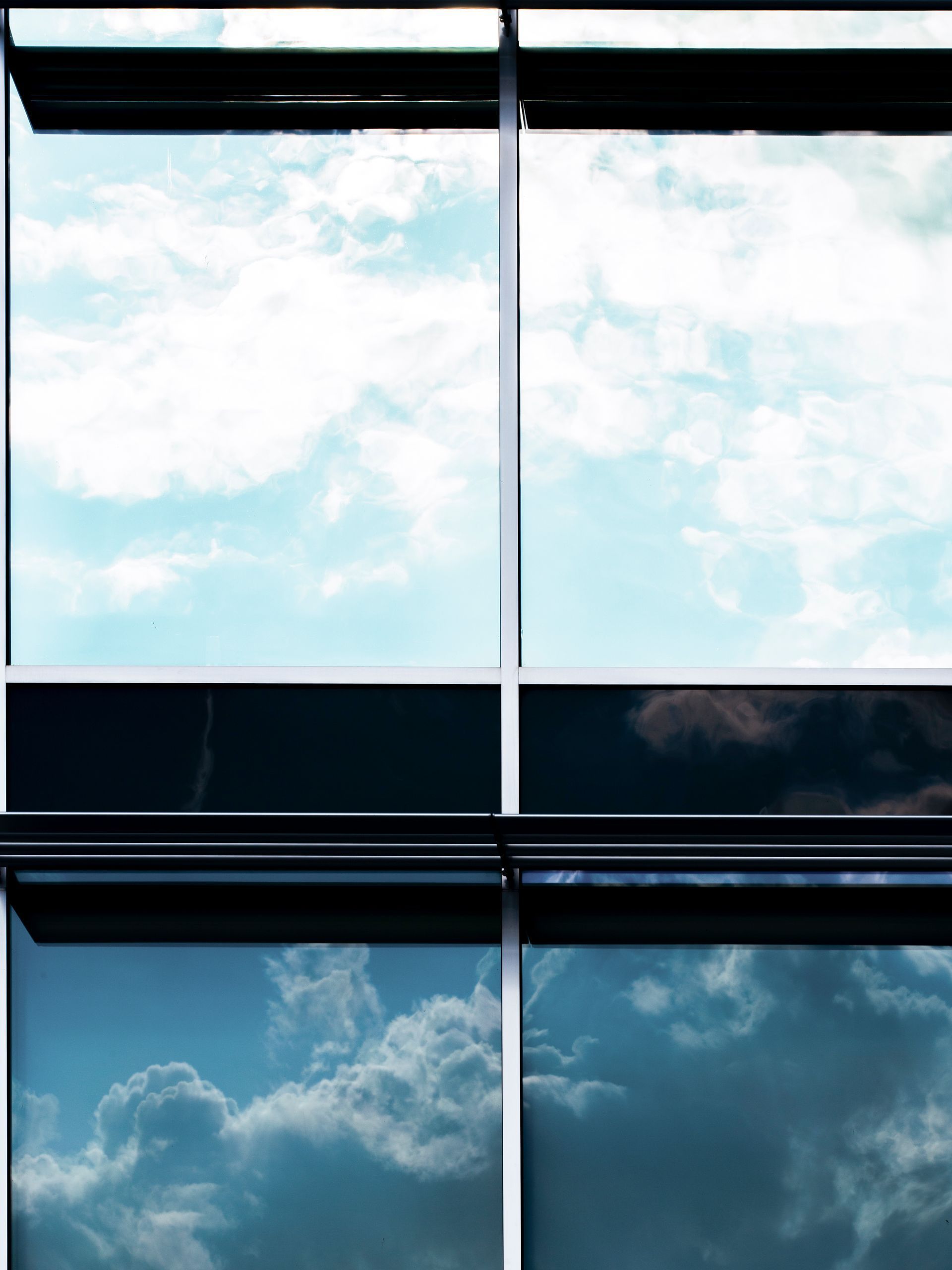 A building with a lot of windows and a blue sky reflected in the windows.