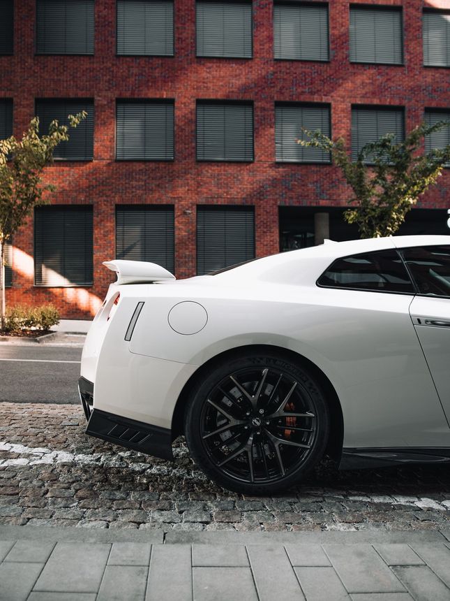 A white sports car is parked in front of a brick building.