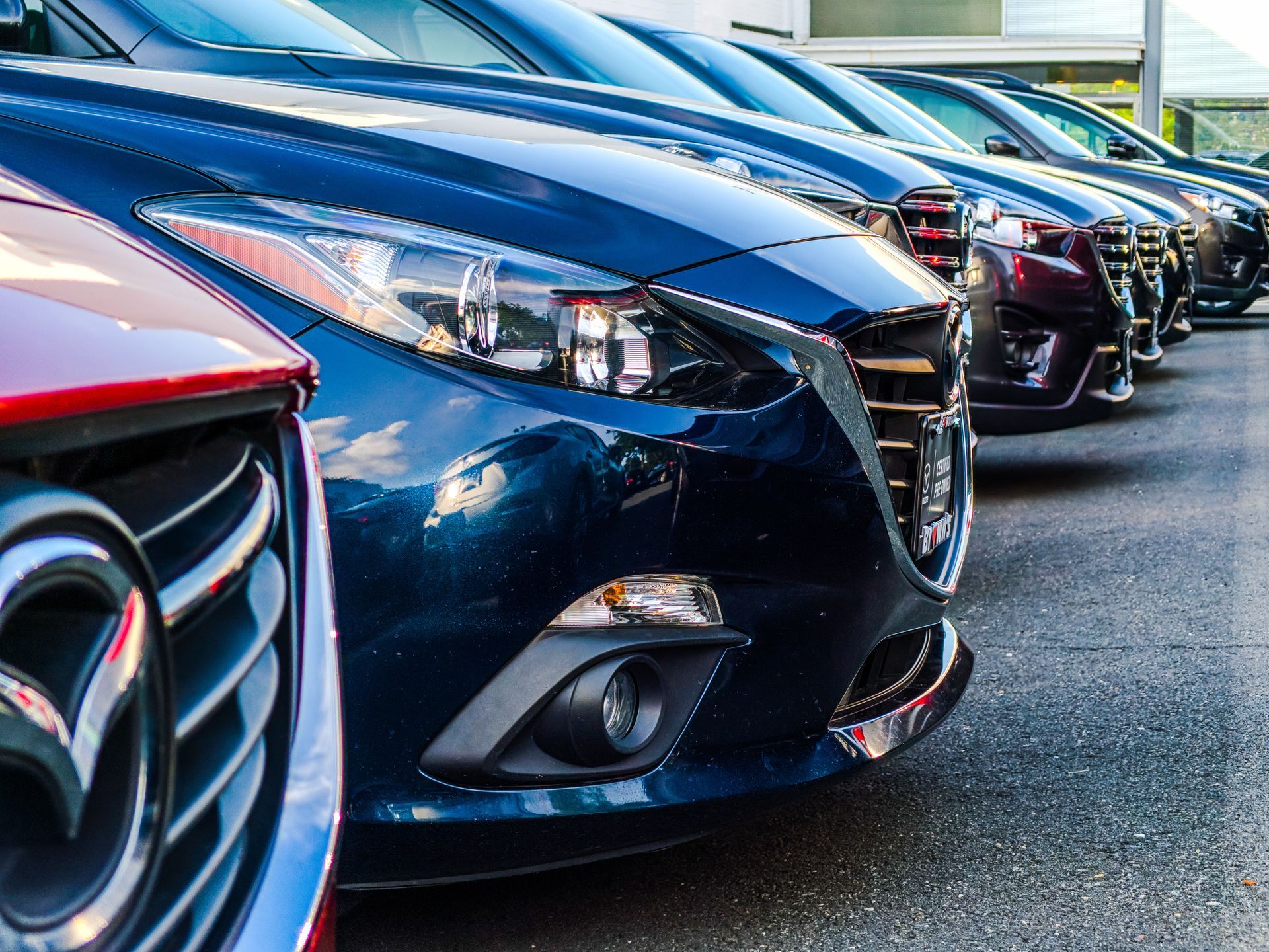 A row of cars are parked next to each other in a parking lot.