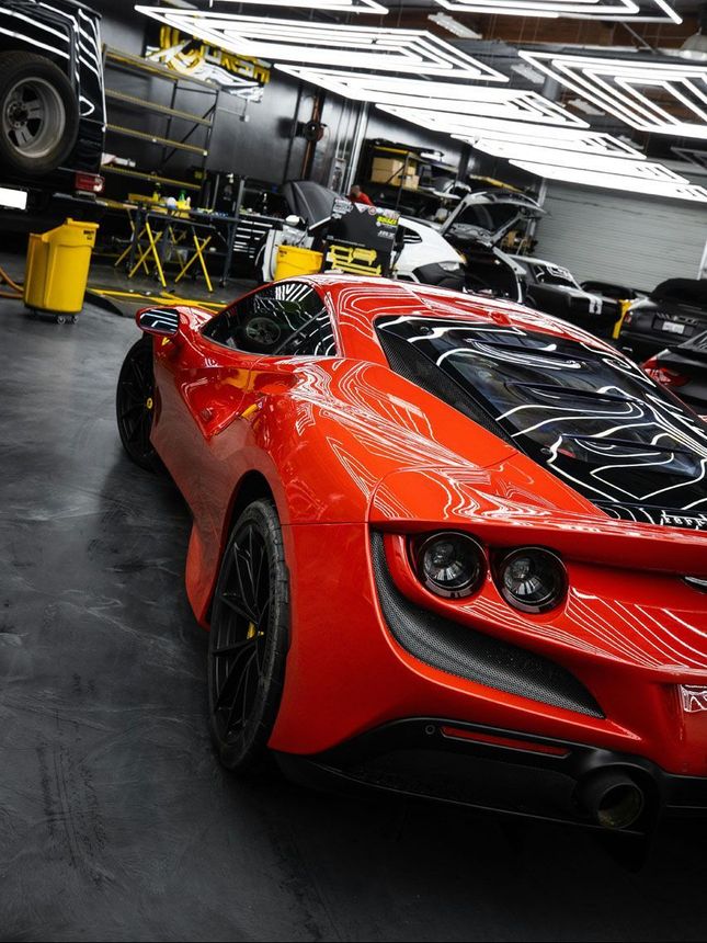 A red sports car is parked in a garage