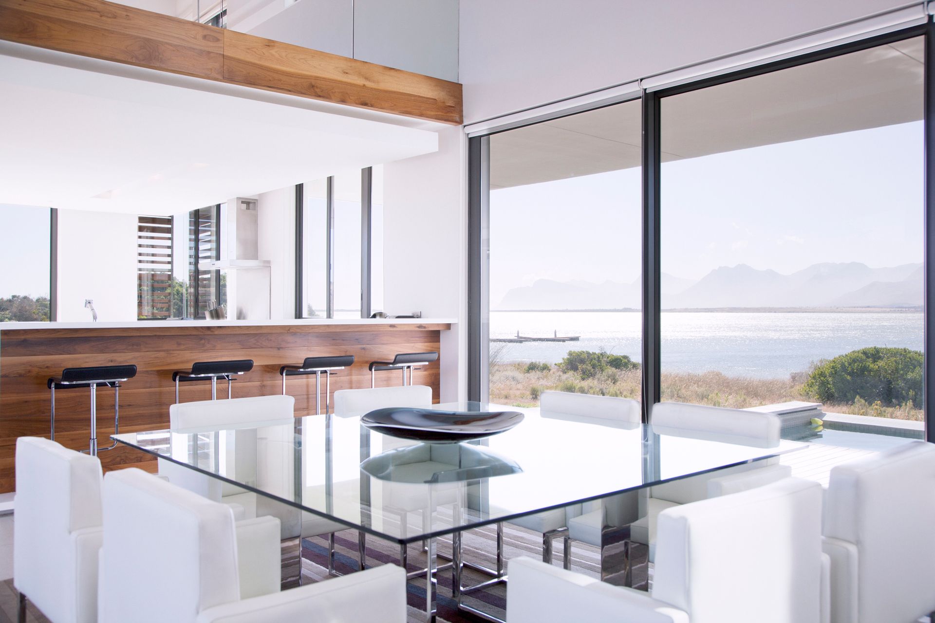 A dining room with a glass table and white chairs
