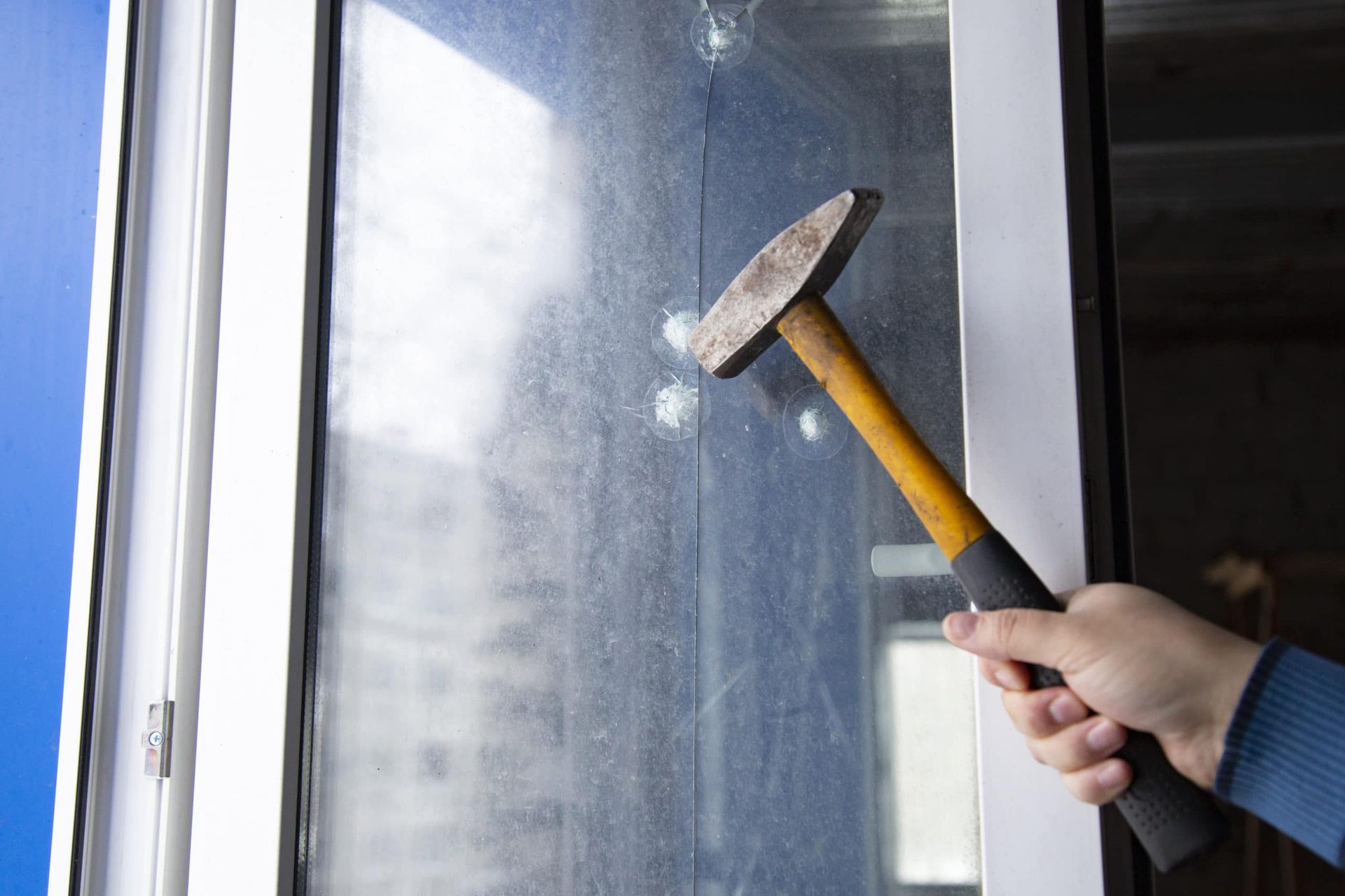 A person is holding a hammer in front of a window.