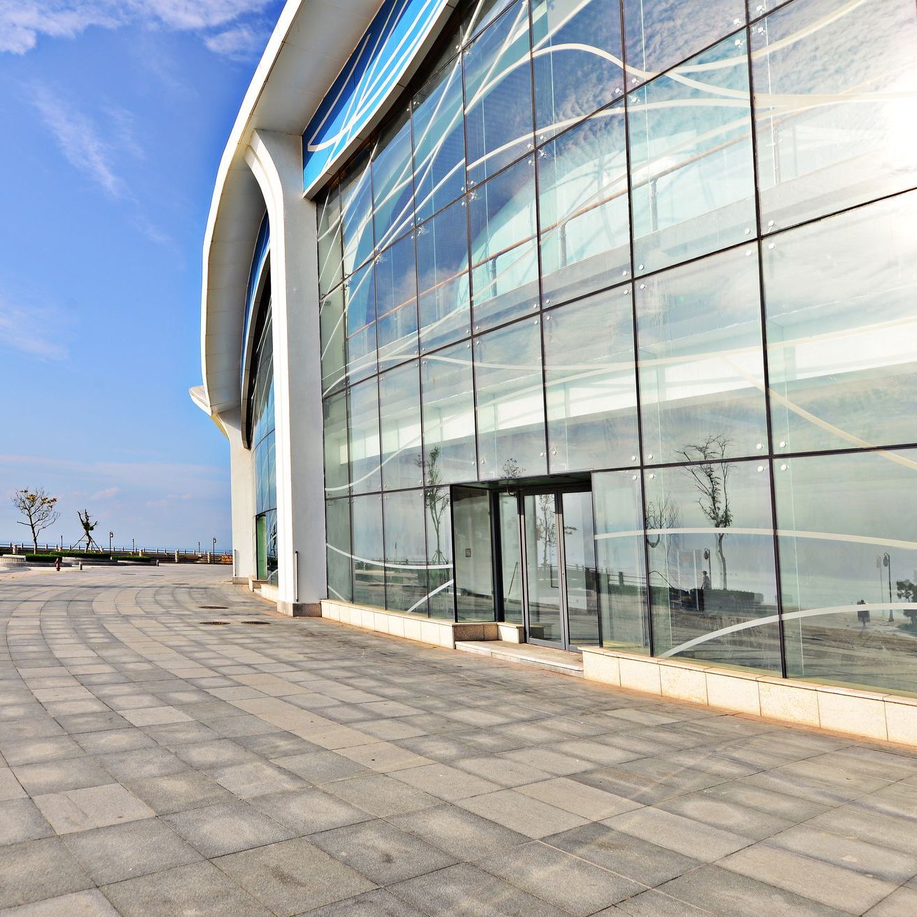 A large glass building with a brick walkway in front of it