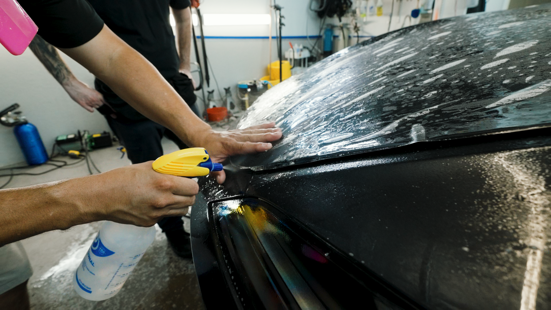 A man is spraying a car with a spray bottle.