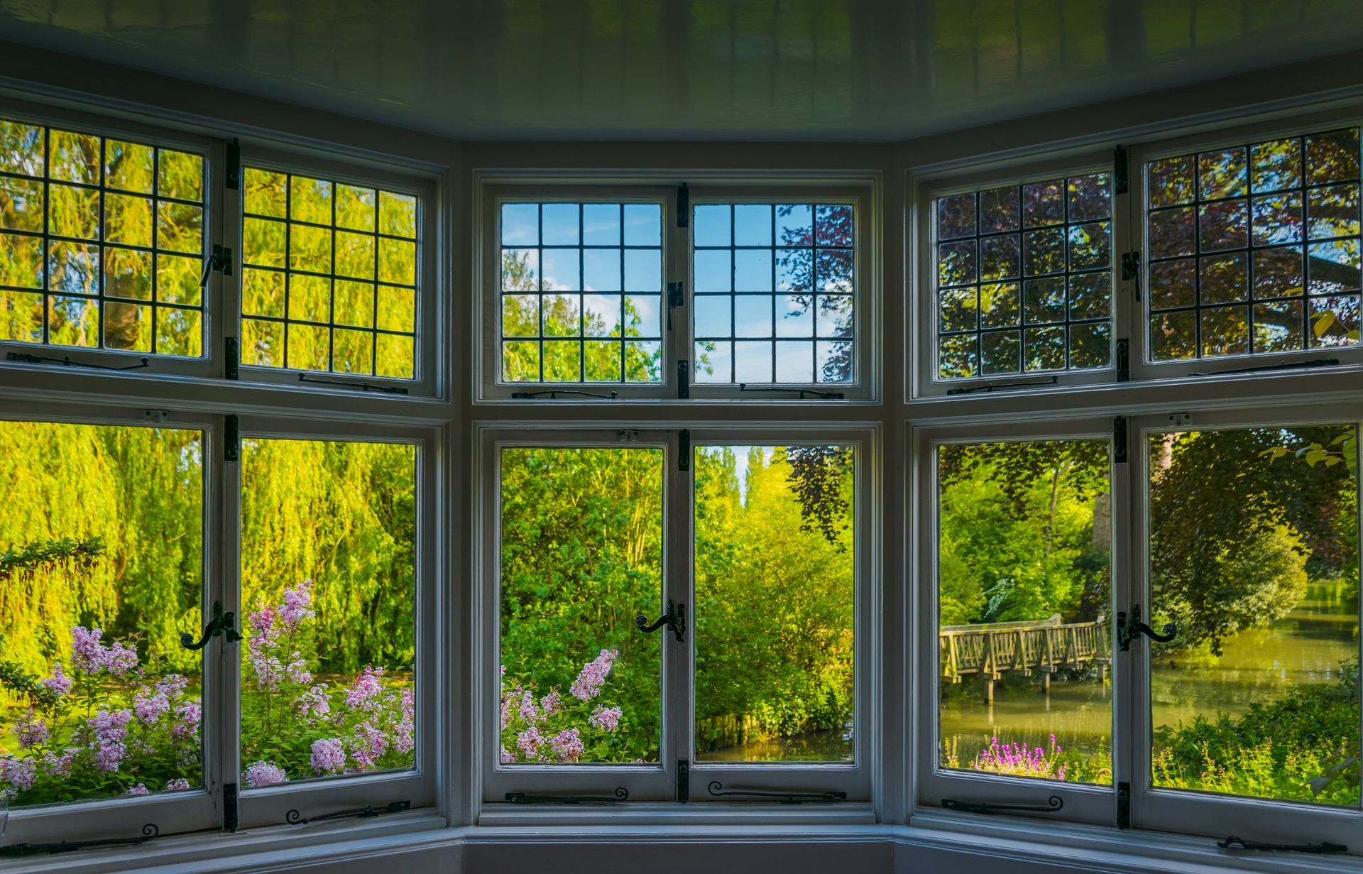 A room with a lot of windows and a view of a garden.