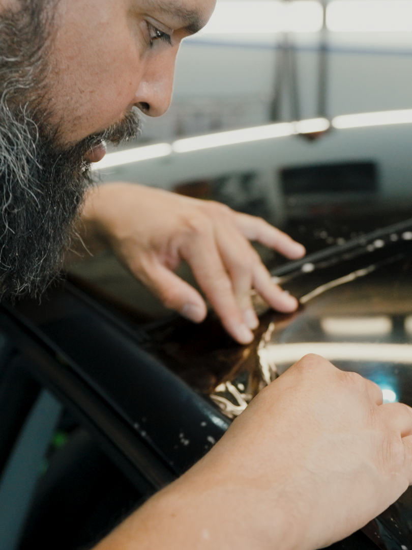 A man with a beard is working on a car