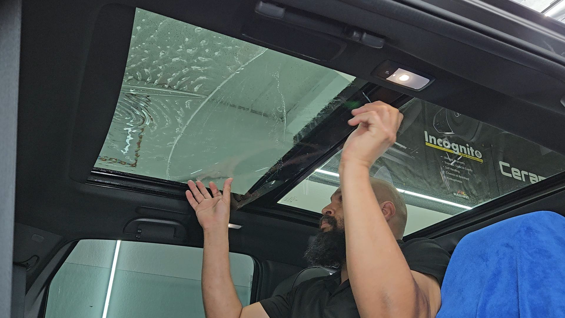 A man is cleaning the sunroof of a car.