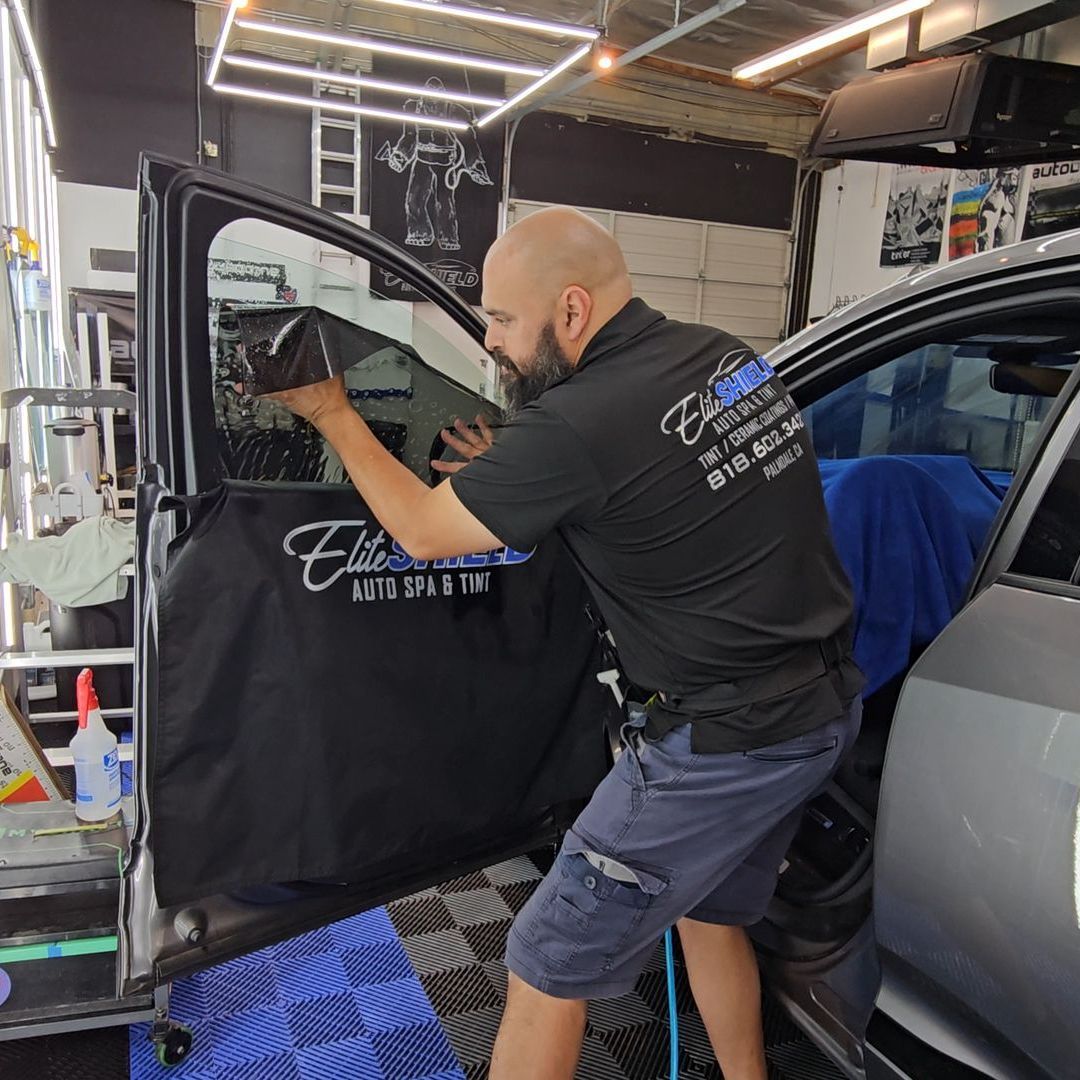 A man in a black shirt is working on a car in a garage.