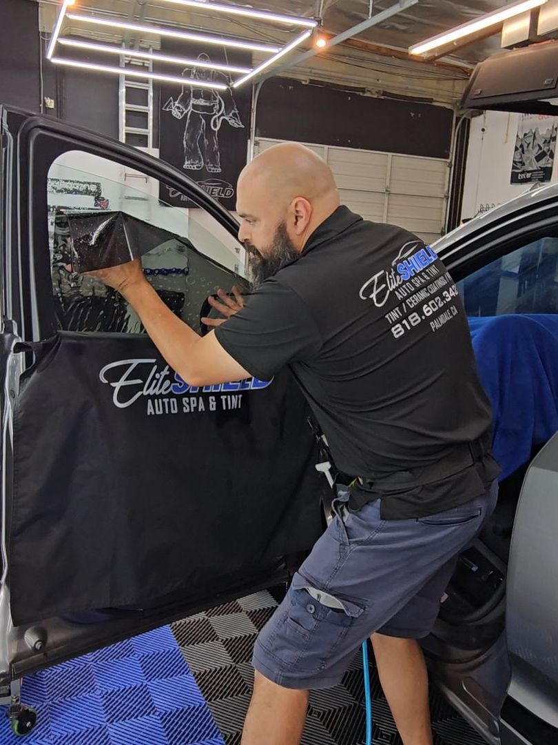 A man is cleaning the windows of a car in a garage.