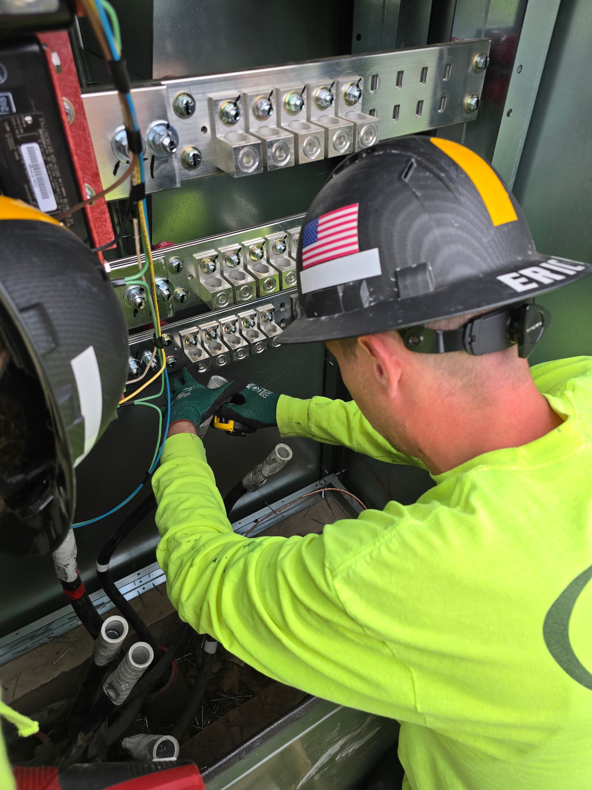 A technician works on an open standby generator outdoors, using a power drill to perform maintenance.