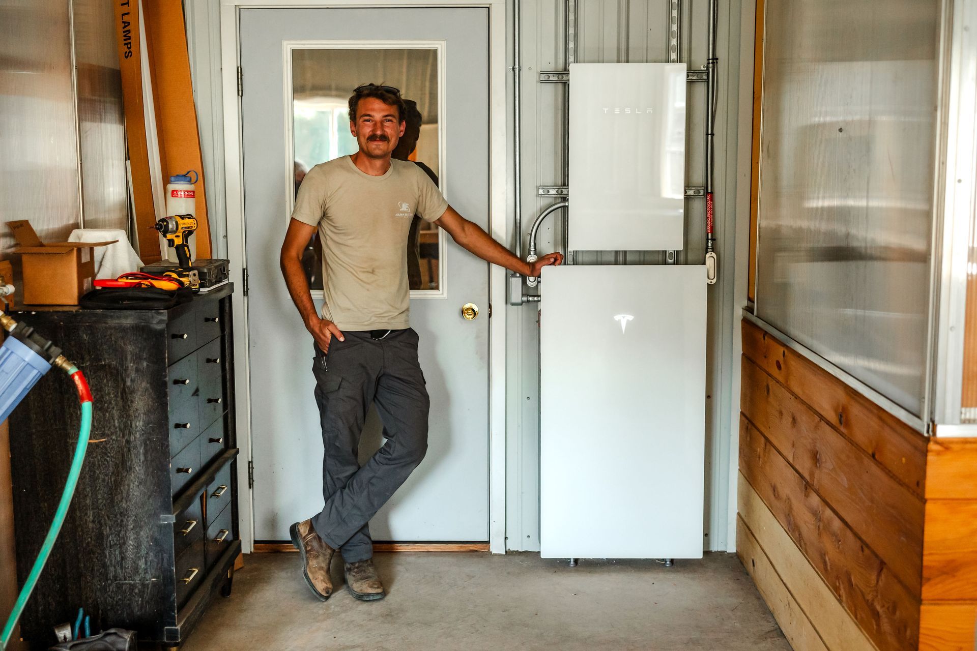 Man standing in a doorway beside a white appliance in a narrow indoor corridor