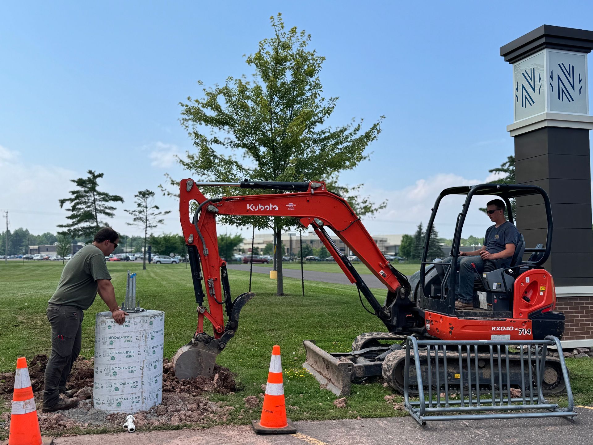 A construction crew operates a yellow horizontal directional drill in a grassy field with utility vehicles parked nearby.