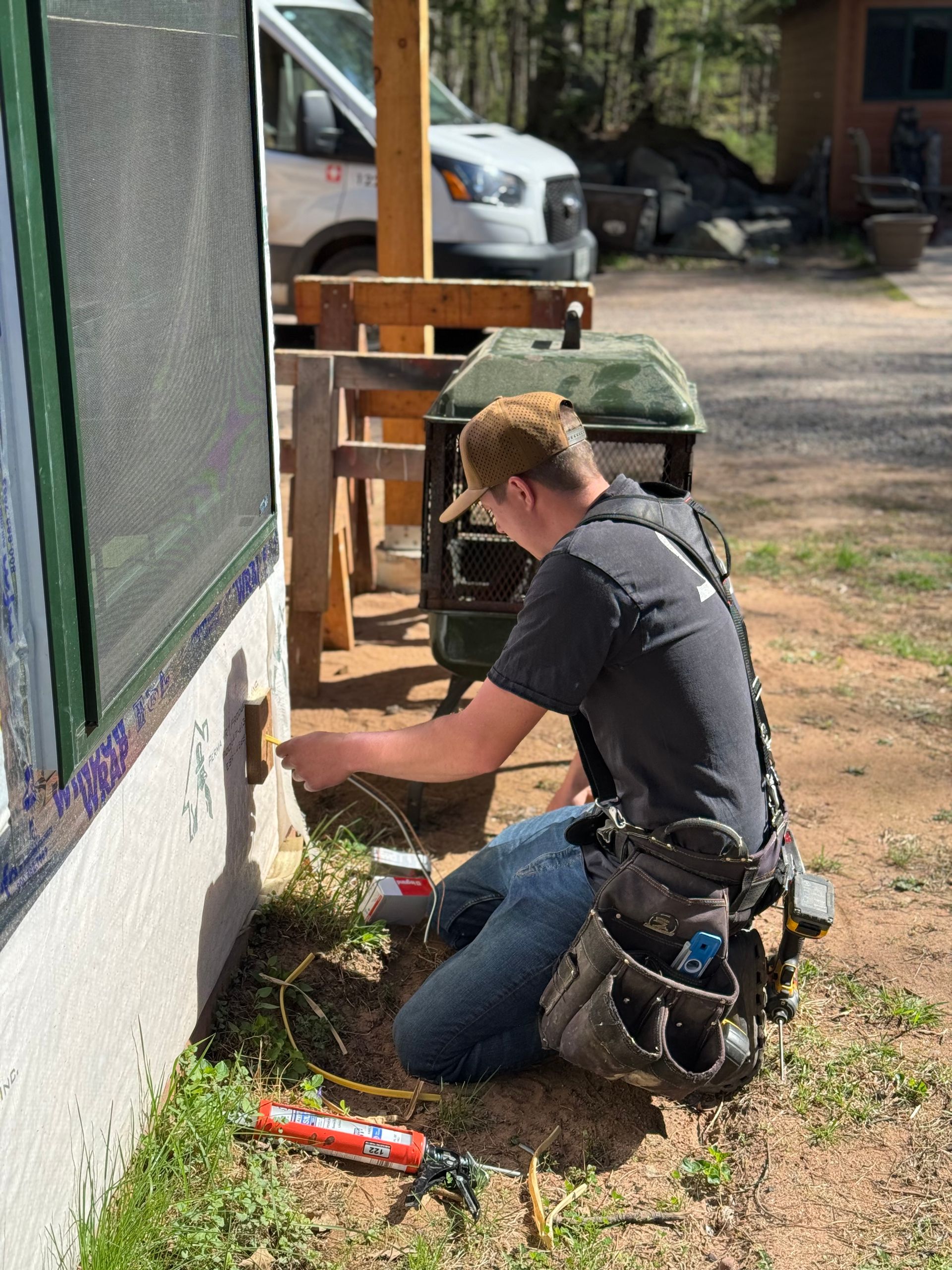 Hands in black gloves use wire strippers to strip insulation from blue and green electrical wires.