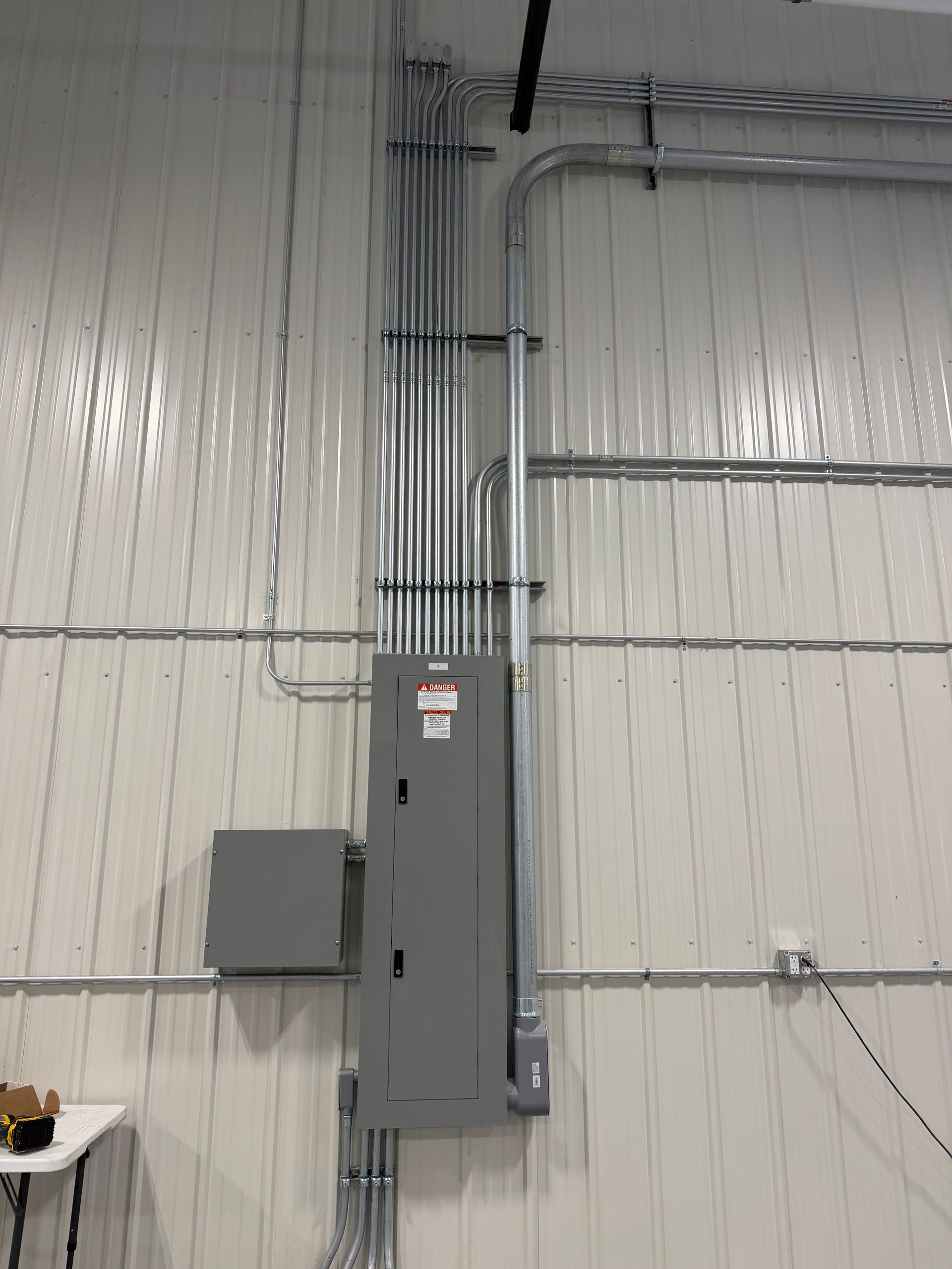 Gray electrical panel with conduit and wall-mounted box in an industrial interior