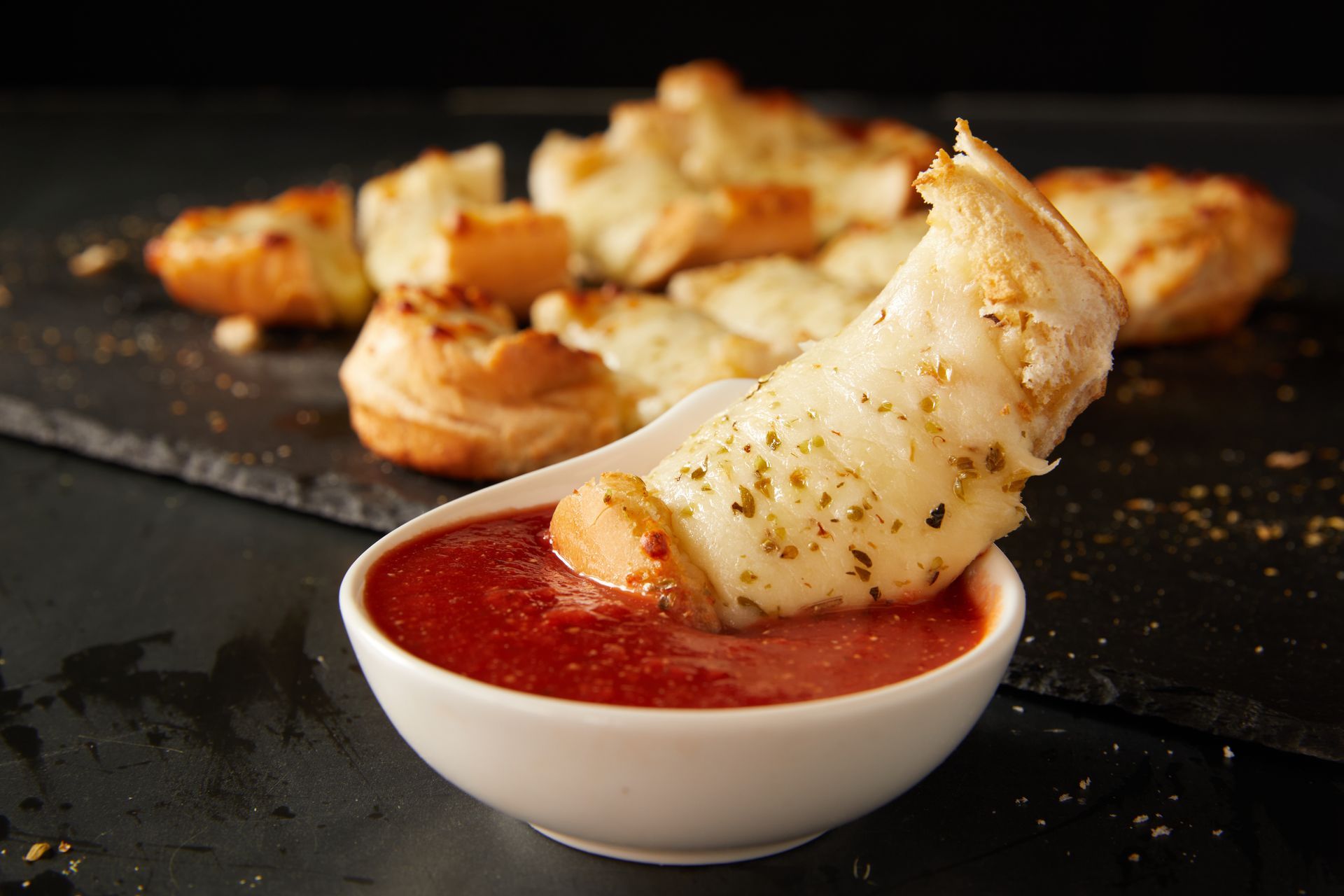 A close up of a bowl of sauce with a piece of cheese sticking out of it.