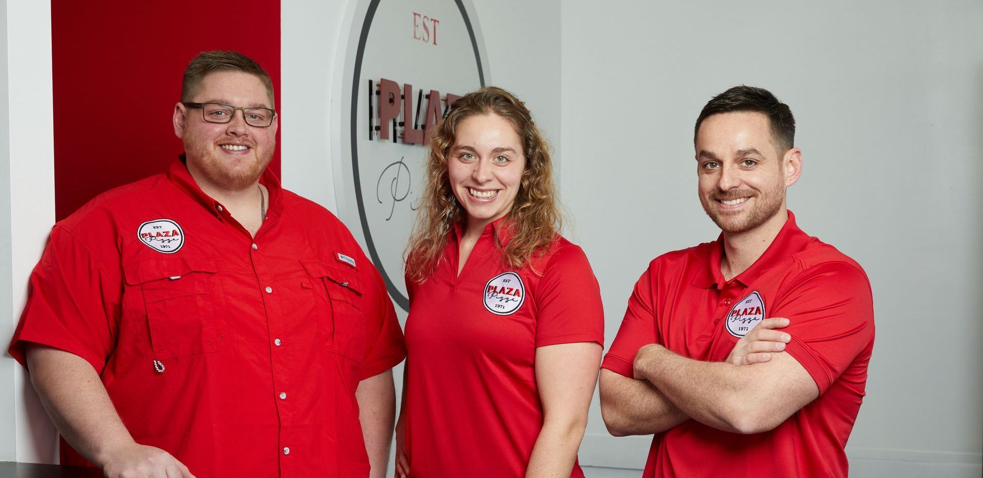 Three people in red shirts are posing for a picture.