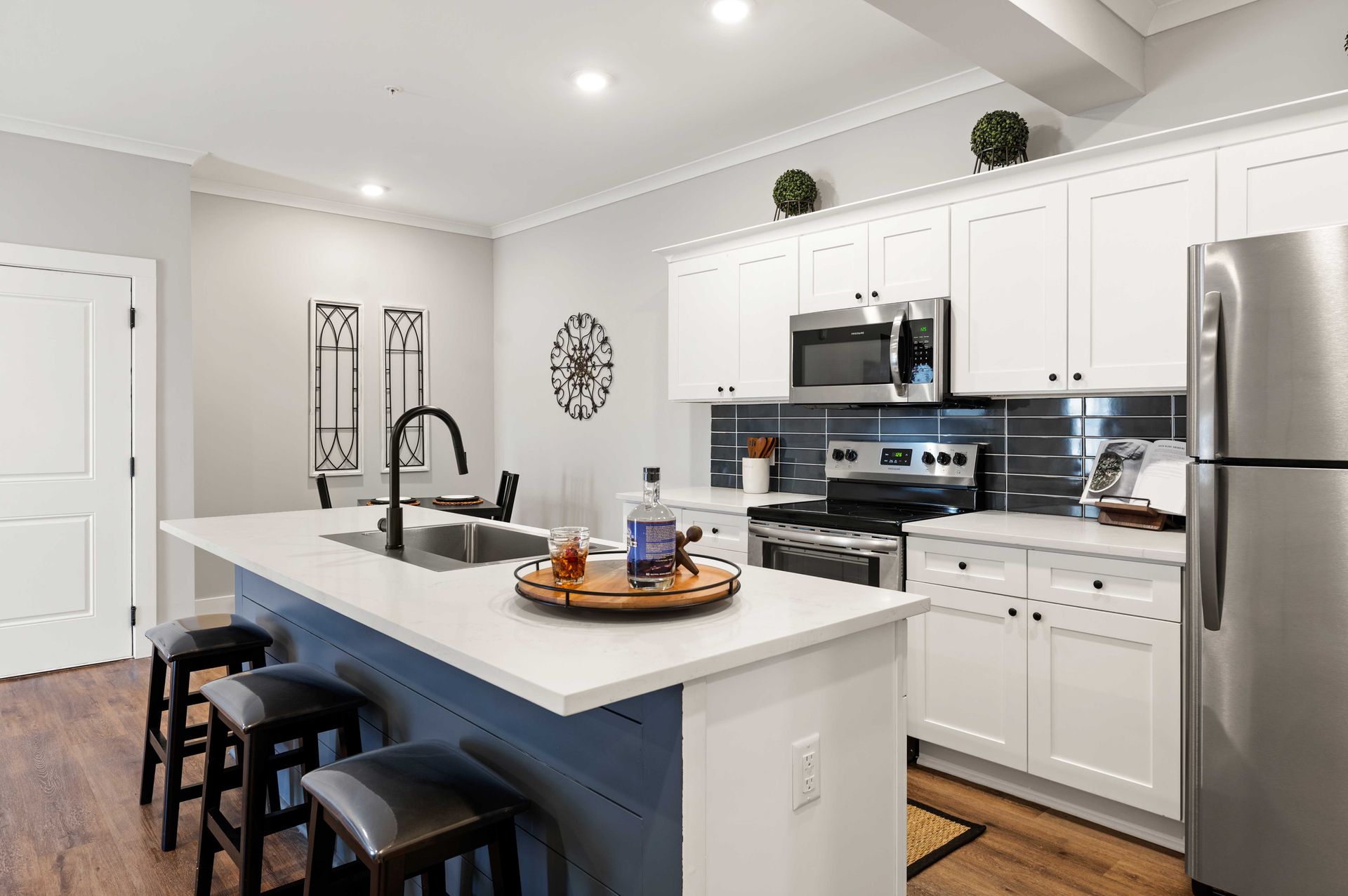 Pointe Grand Columbia Apartment Homes features a kitchen with white shaker soft-close cabinetry, stainless steel appliances, quartz countertops, and a subway tile backsplash.
