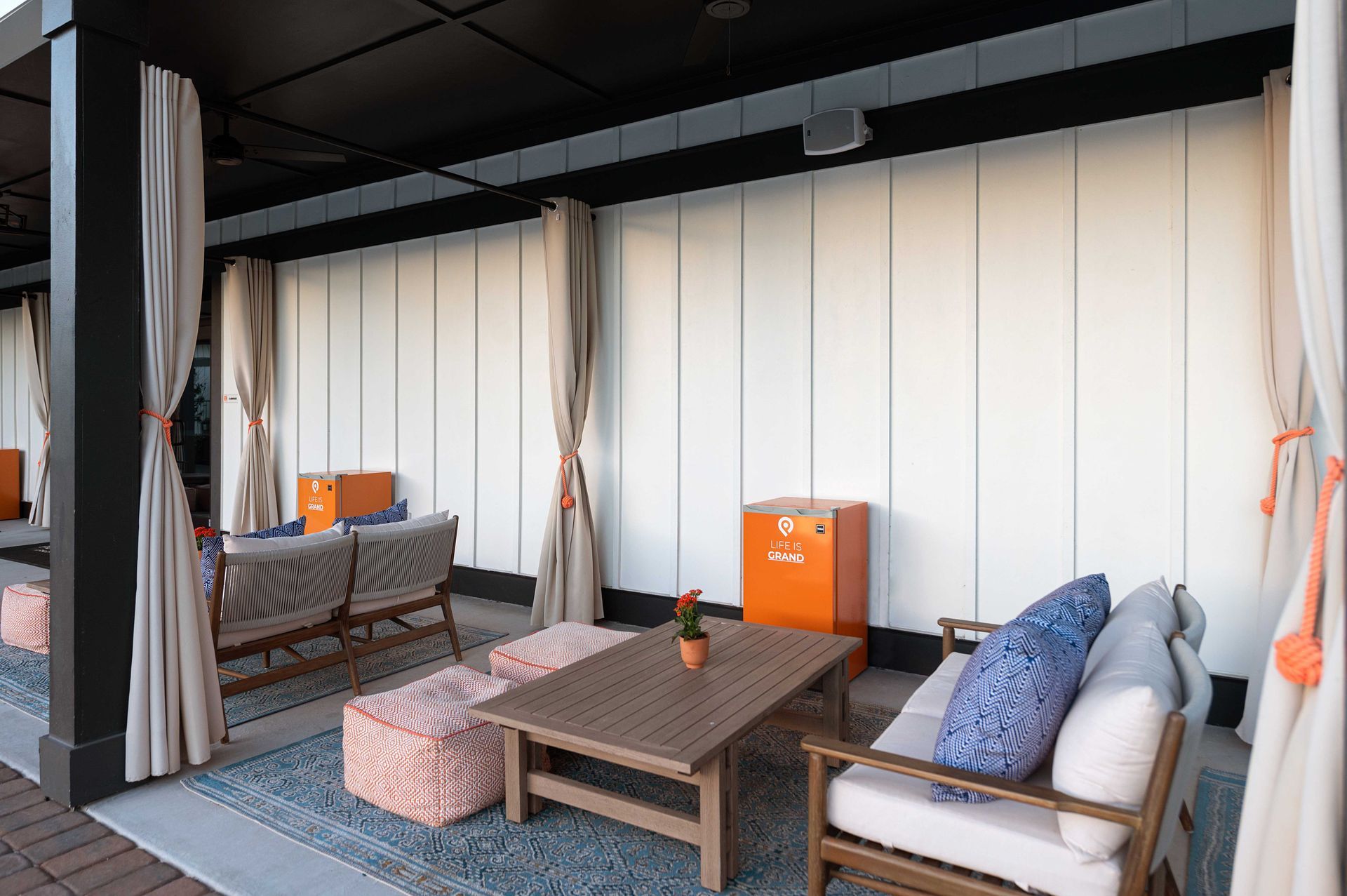 Poolside patio with a couch, chair, table, and curtains at Pointe Grand Columbia apartments in Columbia, SC..