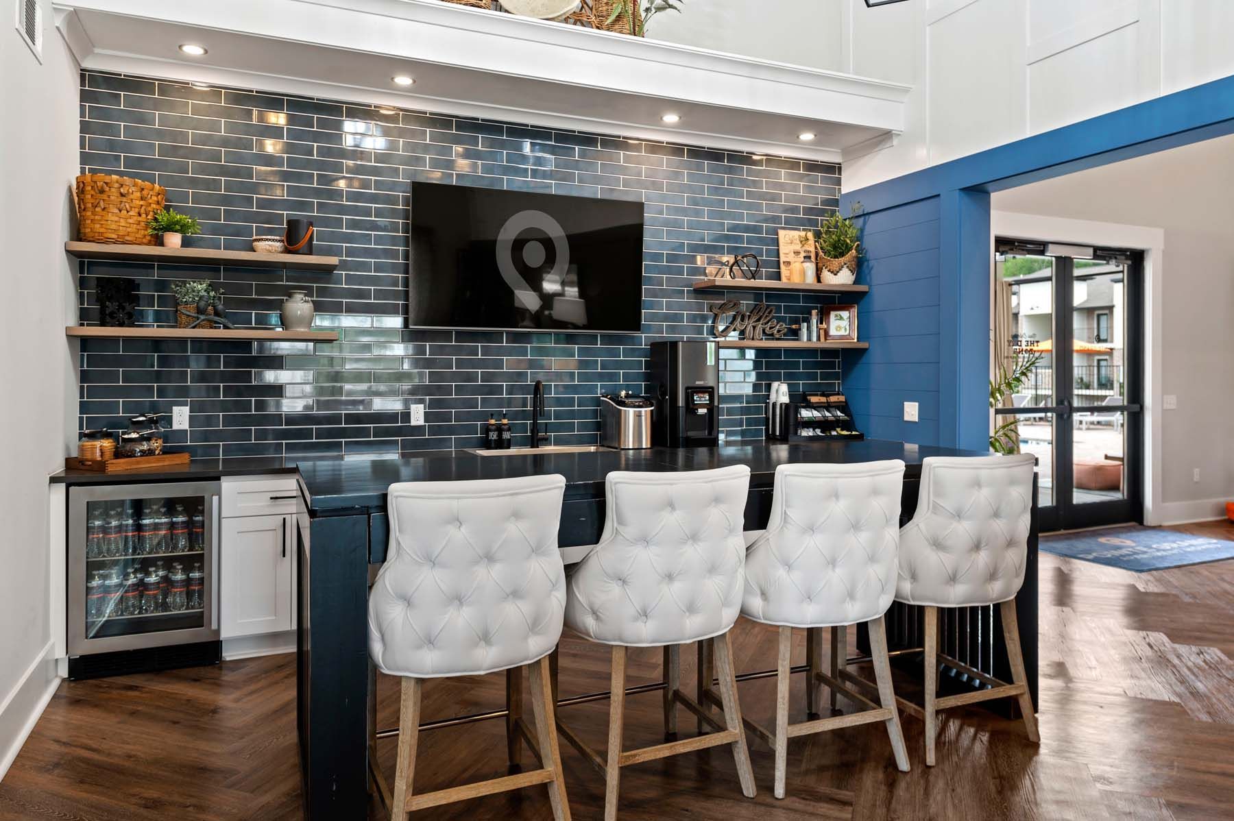 Clubhouse kitchen with a bar, chairs, and television at Pointe Grand Columbia apartments in Columbia, SC.