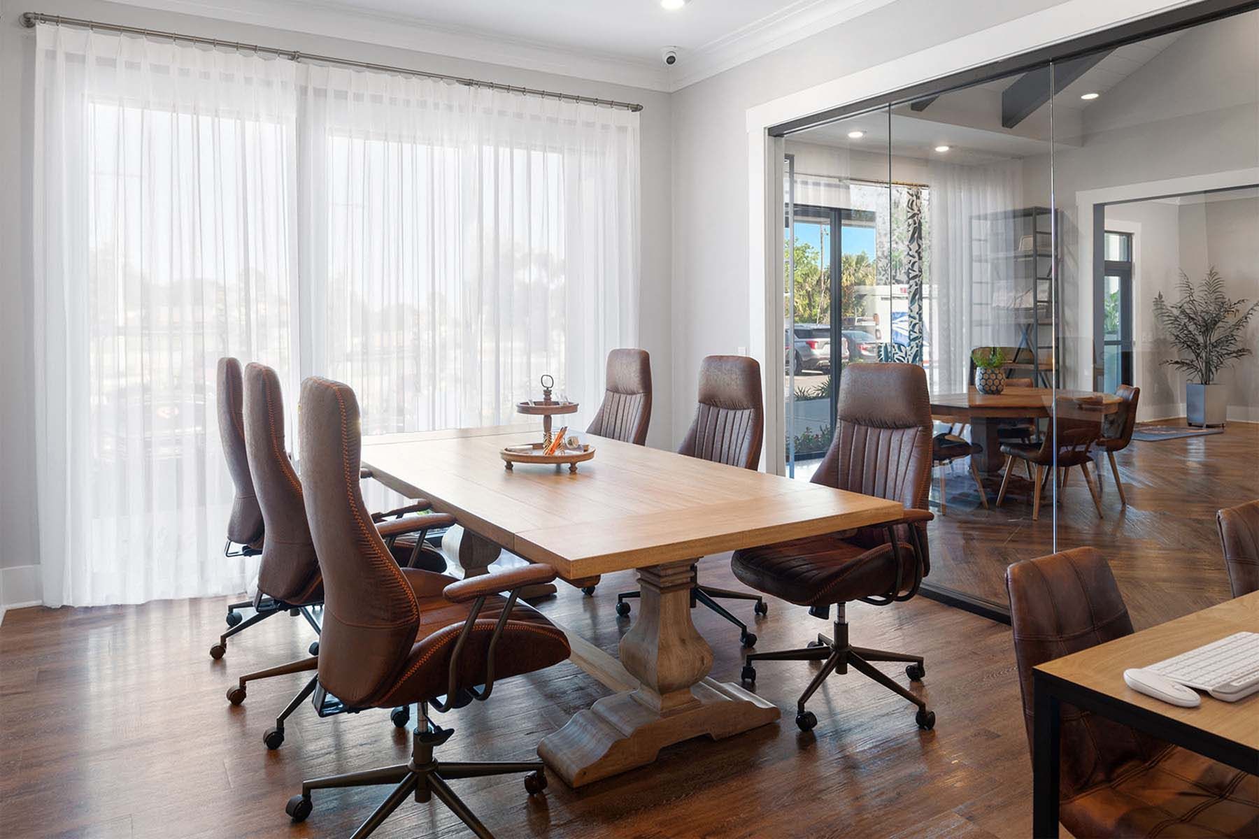 A business conference room with a long wooden table and chairs at Pointe Grand Columbia apartments in Columbia, SC.