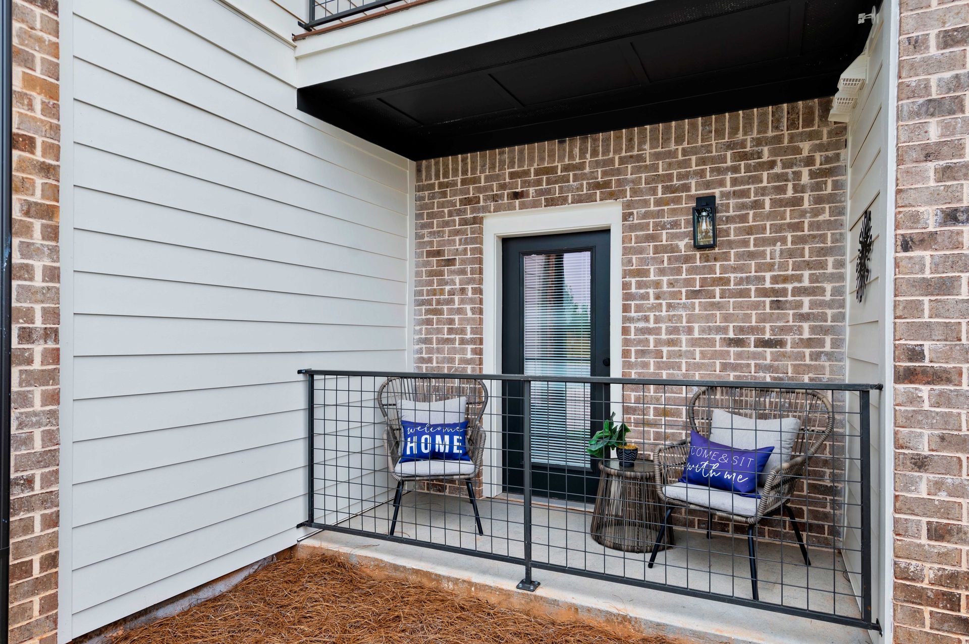 Pointe Grand Columbia Apartment Homes' covered balcony with a fence, outdoor chairs, coffee table, and lighting.
