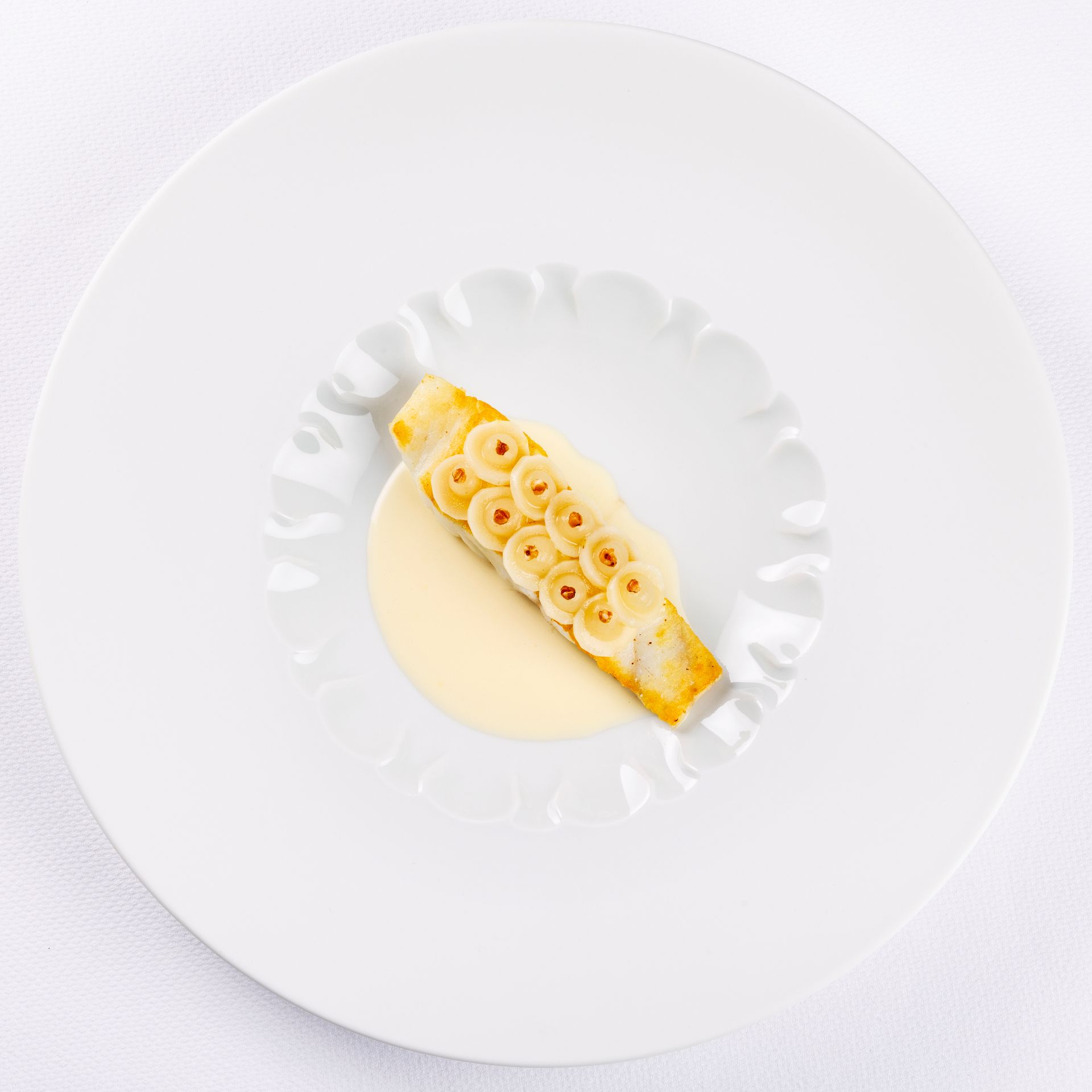 Een wit bord met daarop een stuk eten op tafel.