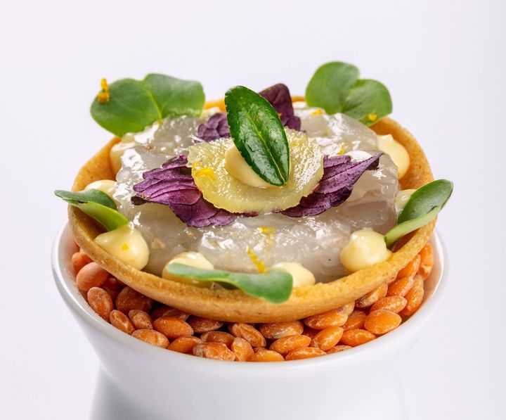 A close up of a bowl of food with beans and vegetables on a table.