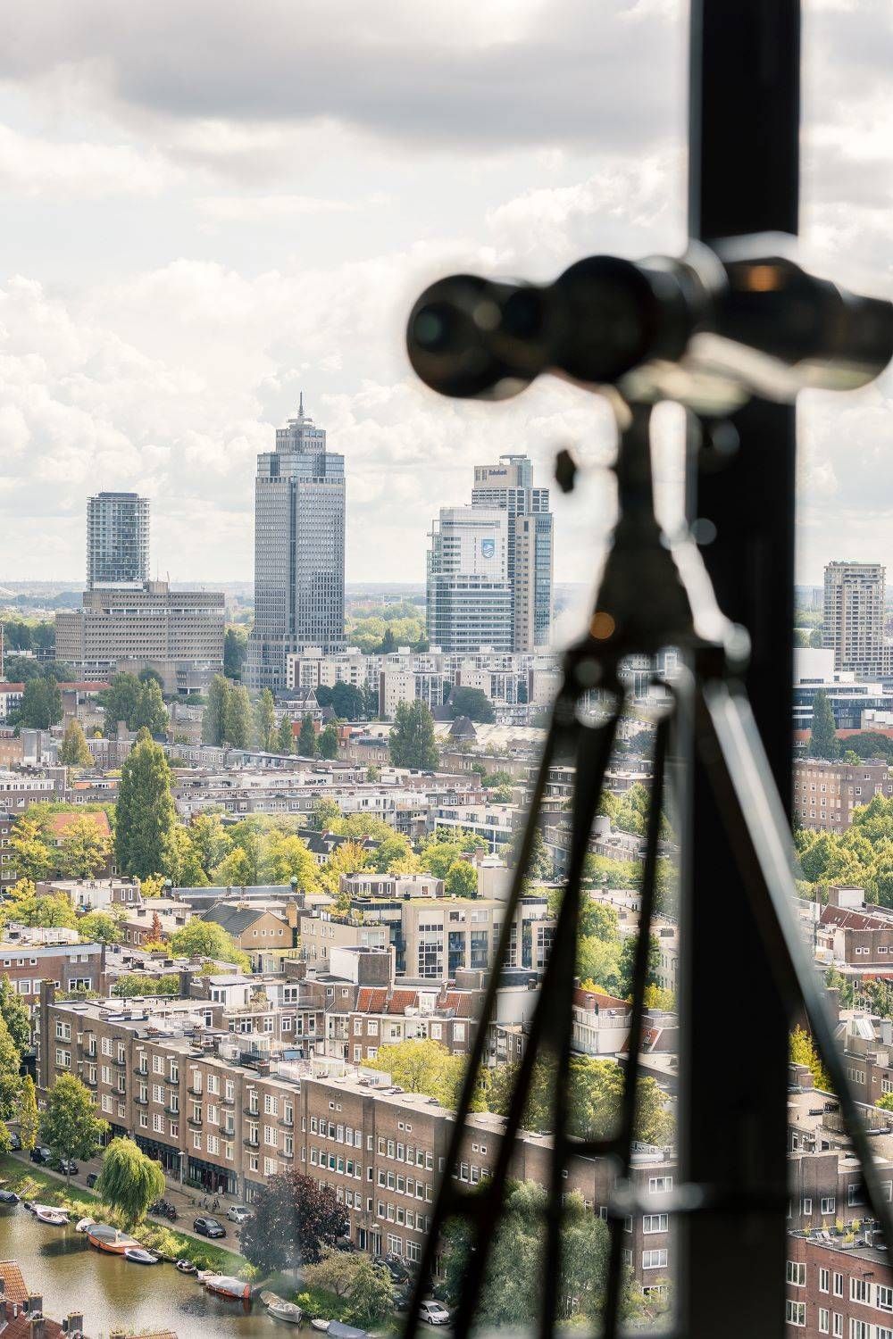 Een telescoop staat op een statief en kijkt uit over een stad.