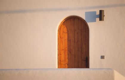 There is a wooden door in the middle of a white wall.