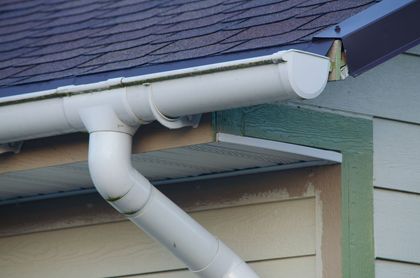 A close up of a white gutter on the side of a house.