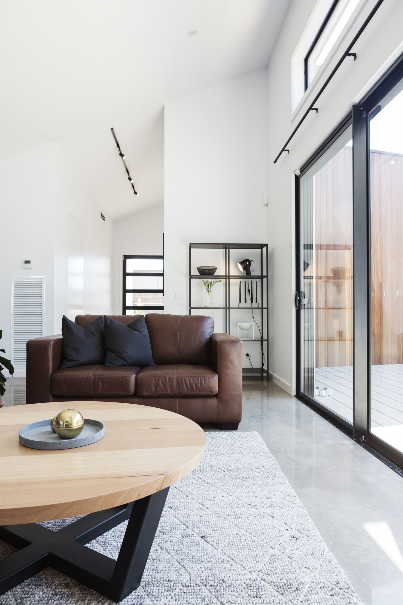 A living room with a brown couch and a wooden table