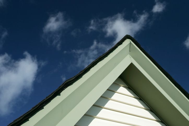 Looking up at the roof of a house with a blue sky in the background