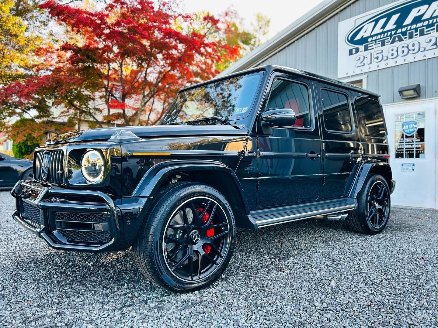 Black Mercedes-Benz G-Wagon SUV parked in front of a building. Red brake calipers visible on tires.