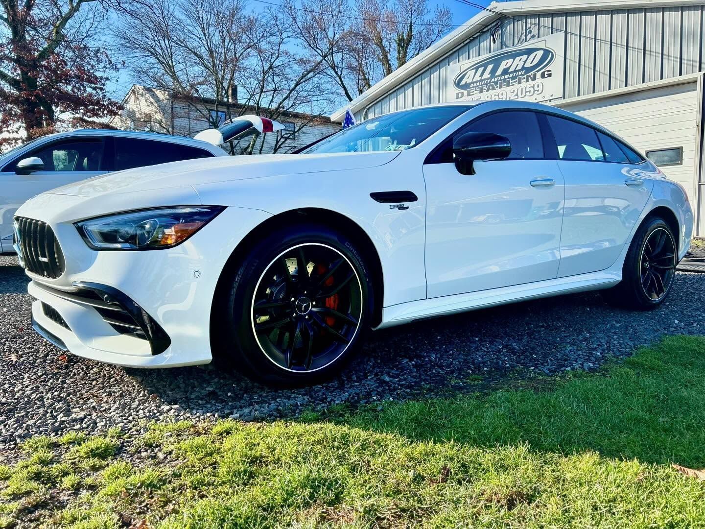 A person wearing black gloves is polishing the hood of a red car.