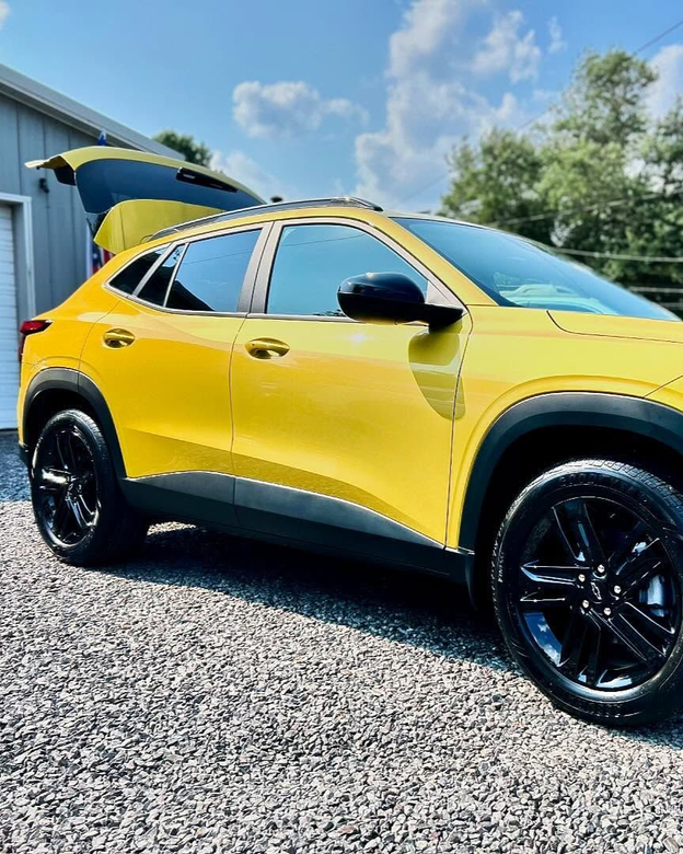 A car is covered in plastic wrap in a garage.